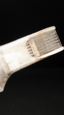 Needles for a tattoo machine, close-up. On a black background. Vertical video.