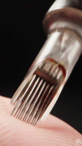 Needles for a tattoo machine, close-up. On a black background. Vertical video.