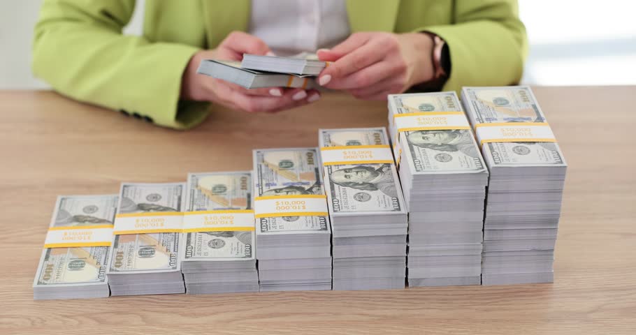 Woman arranges dollar bills in neat stacks on table. Female places money cash creating organized and presentable arrangement of steps showing success slow motion