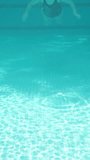 Blue swimming pool, underwater shooting, sunny day. A plump young woman swims in a closed swimsuit Vertical video.