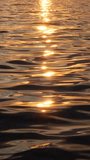 The reflection of sunlight on the surface of the lake at dusk at sunset. The sun's rays twinkle on the water. Vertical video for shorts.