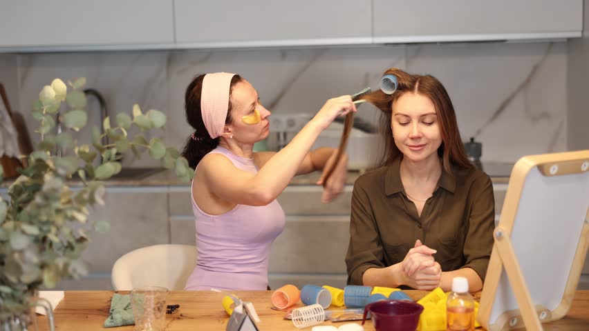 Adult woman doing hair perm with curlers to young woman Royalty-Free Stock Footage #3456953785