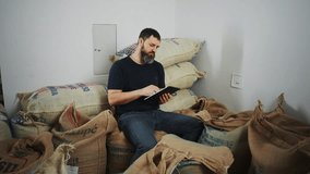 Man in a warehouse with bags of coffee keeps records with a tablet. Small business concept - Powered by Shutterstock - Get 15% off with code: PIKWIZARD15