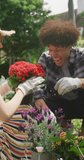 Vertical video of happy diverse couple working in garden on sunny day. Spending quality time at home concept.