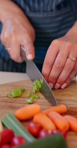 Vegetables knife, hands and person cutting celery, ingredients and prepare food on wooden board. Nutritionist salad, kitchen utensils tools or closeup chef slice carrot, tomato and cooking dinner Royalty-Free Stock Footage #3457022671