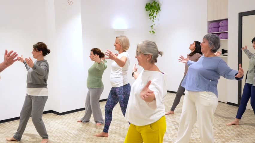 Group of mature adult and caucasian sportive women opening arms during qi gong class Royalty-Free Stock Footage #3457043123