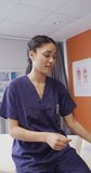 Vertical video of portrait of asian female doctor smiling at hospital. Medicine, healthcare, lifestyle and hospital concept.
