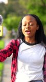 Young african woman recording a video with a mobile phone in an urban park in the city