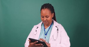 Young Black female doctor works on tablet, smiles at the camera