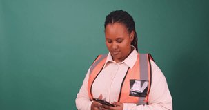 Beautiful young Black female construction worker talking on cellphone, architect