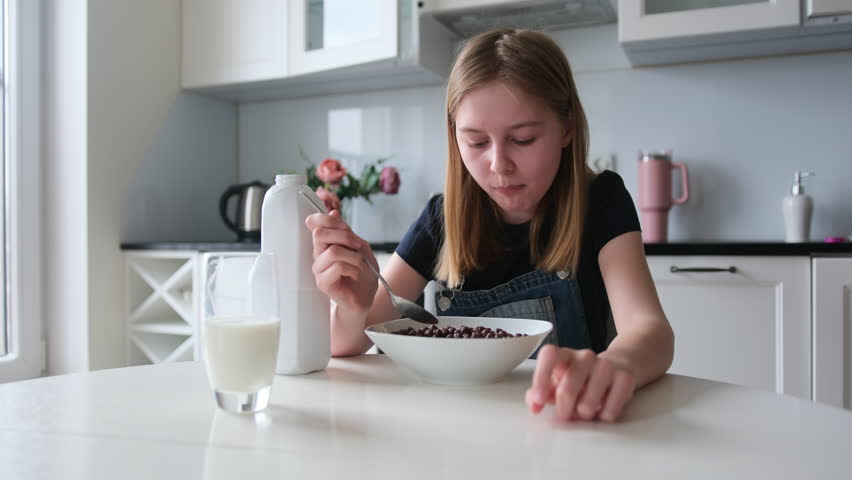 Girl Having Brown Chocolate Balls Cereal For Breakfast In The Kitchen In The Morning Royalty-Free Stock Footage #3457153007