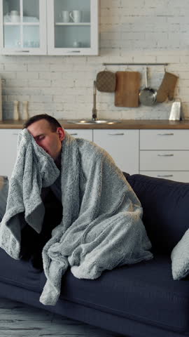 Sick young man suffering from flu at home. Pandemic. Quarantine concept. Vertical video.