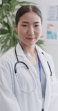 Vertical video of portrait of happy asian female doctor. Global medicine, health, lifestyle and hospital concept.