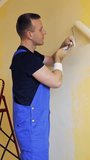 Young worker painting wall in room. Offering professional painting services. Vertical video.