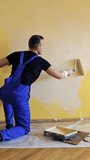 Young worker painting wall in room. Repair, building and home concept. Vertical video.