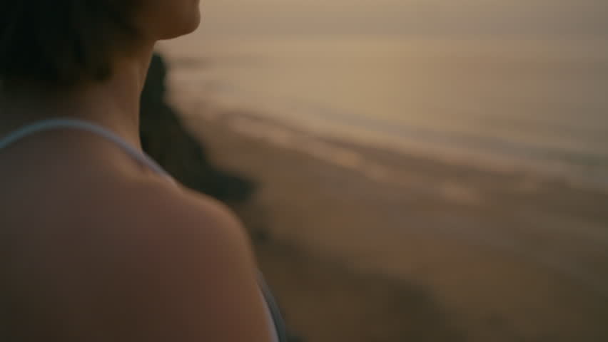 Close up of Woman doing yoga on the edge of the cliff by the ocean at sunset, Fuerteventura, Spain