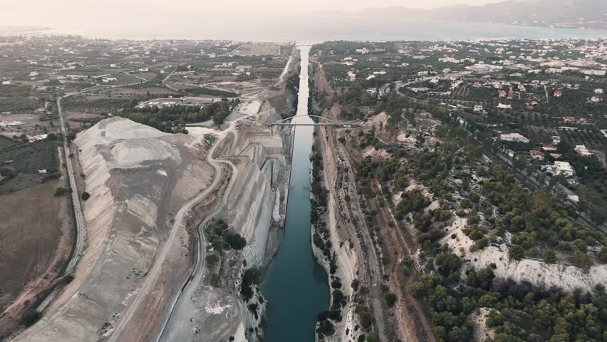 Drone shot of the natural wonder of the Isthmus of Corinth, a narrow strip of land that separates two bodies of water in Greece, connecting the Peloponnese peninsula to the mainland of Greece.
