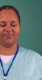 Black female doctor uses stethoscope to listen to heartbeat, in scrubs