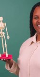 Young Black female doctor teaches human anatomy with model skeleton