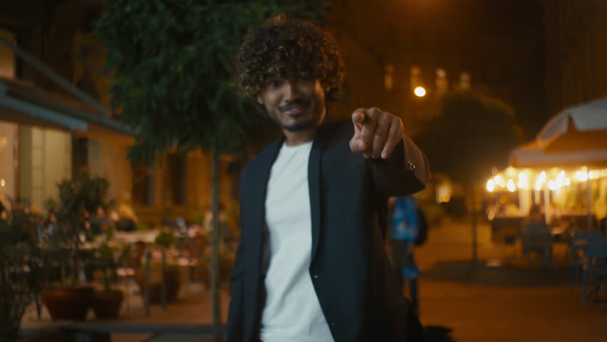 Handsome Indian Arabian Latino man pointing finger at camera beckon invitation gesture hand sign greeting motivation ethnicity posing positive cheerful guy offer welcome call come here city outdoors
