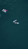 Aerial drone footage people learning water sports standup paddleboarding sup boarding. Vertical video.