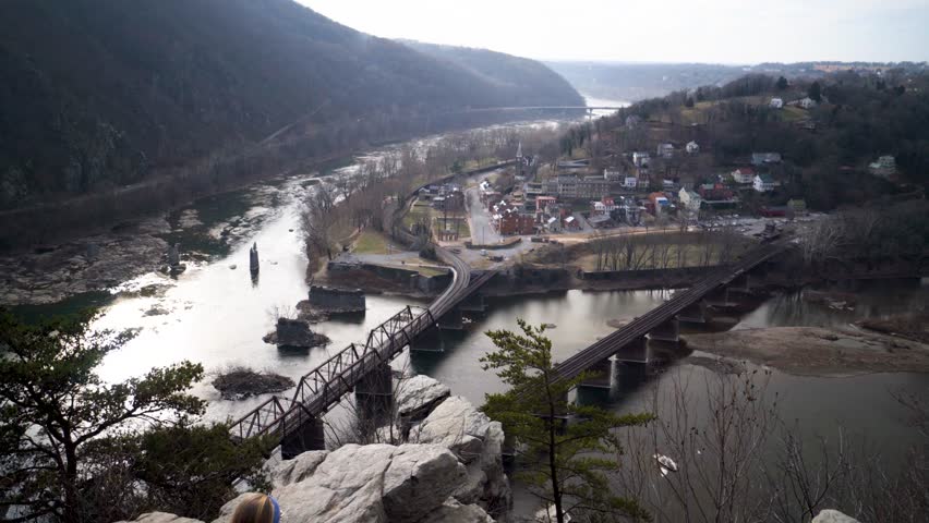 Camera booms down from view of Harpers Ferry National Park to reveal mature blonde woman enjoying the view at an overlook at Maryland Heights.