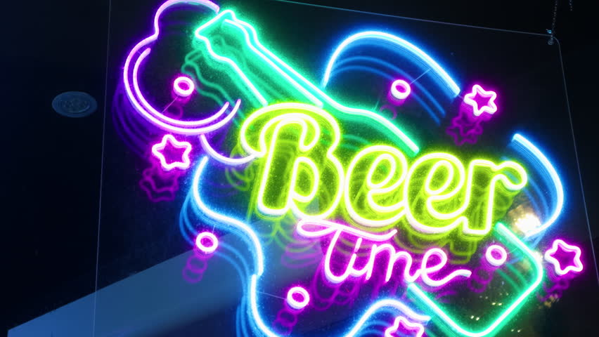 A neon sign is hanging on a pole in a dark room