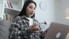 Sad asian young woman talk with psychotherapist at online distance remote counselling session indoors Depressed female discussing problem with psychological support by laptop computer at home
