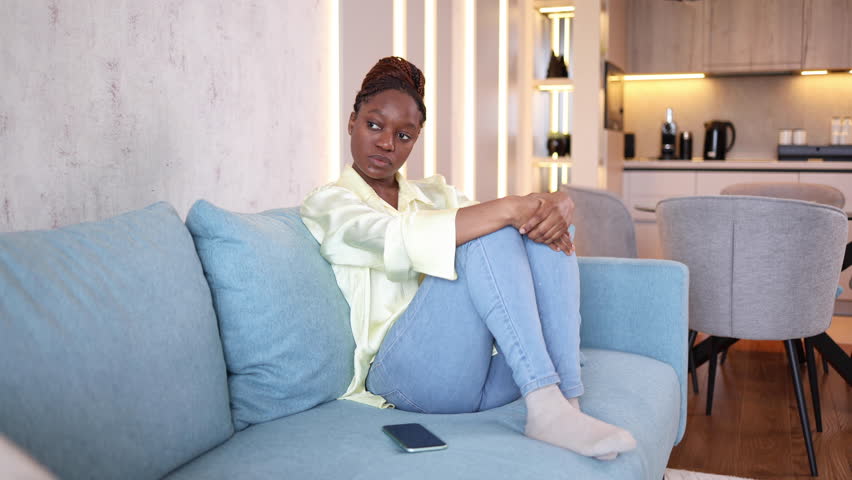 Young African American woman sitting alone and depressed at her living room Royalty-Free Stock Footage #3457292481