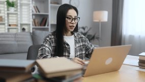 Portrait of beautiful asian woman with glasses having video call conference meeting showing graphics by laptop computer at home Smiling student talking on working or personal conversation indoors