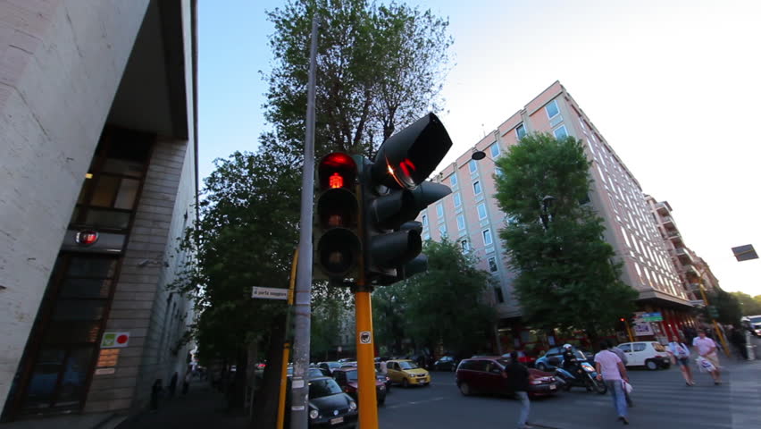 A corner stoplight stays a consistent red as people cross the street