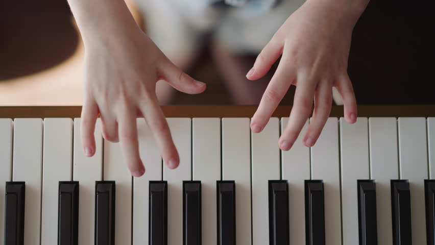 Child musician plays piano. Girl hands press keys in connected manner. Improving skills of playing musical instrument upper view on blurred background Royalty-Free Stock Footage #3457396279