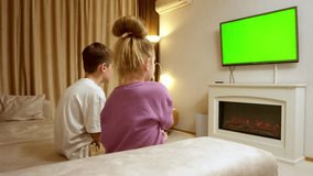 Children in a home interior enjoying playing a game console against a green TV screen background. Game console, video games, technology, recreation.