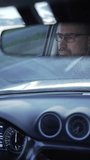 man's eyes with glasses in the rear-view mirror of the car. Driver attentive to the road, in the front glass we see the road as it moves forward, video of driving and travelling.