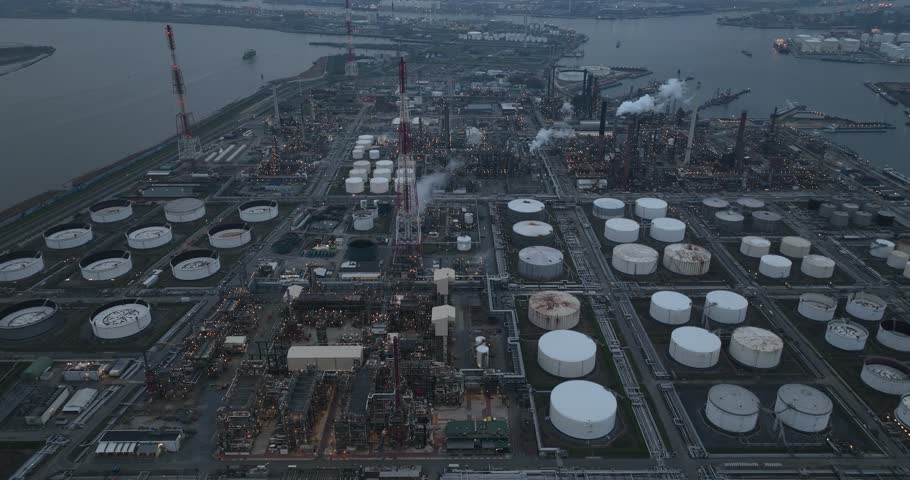 Refineries and the three steam crackers in the port of Antwerp, Belgium at dusk. Petrochemical silos and storage containers. Chemical production, oil and chemical production. Aerial drone view.