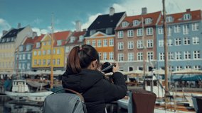 Asian tourist woman backpacker traveler with her camera at Copenhagen Nyhavn, Famous landmark, northern Europe destination, the old town waterfront water canal in the capital Kobenhavn in Denmark. - Powered by Shutterstock - Get 15% off with code: PIKWIZARD15