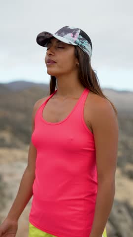 sporty woman sitting on a mountain taking pictures with smartphone