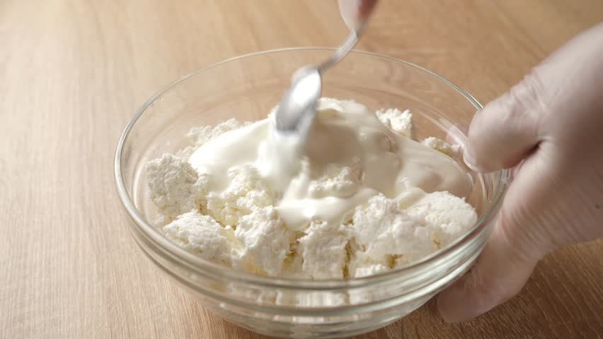 Sour cream is added to sour milk cheese and mixed.