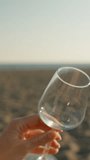 Romantic date on the beach by the sea, sunset and a young woman pours wine into a glass, close-up. Vertical video Social Media