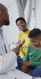 Vertical video of african american male doctor examining child patient at hospital. Medicine, healthcare, lifestyle and hospital concept.