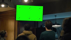 Group of diverse friends sit in sports pub and watch live match broadcast on TV. Fans gathered to cheer and support team playing in tournament. Player scores a goal and crowd celebrate. - Powered by Shutterstock - Get 15% off with code: PIKWIZARD15