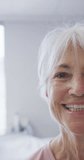 Vertical video of portrait of senior caucasian woman smiling at hospital. Medicine, healthcare, lifestyle and hospital concept.