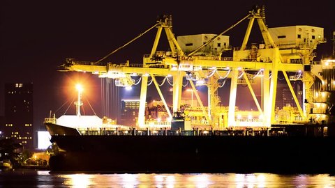 Industrial Container Cargo freight ship with working crane bridge in shipyard at dusk for Logistic Import Export