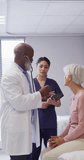 Vertical video of diverse doctors examining senior caucasian female patient at hospital. Medicine, healthcare, lifestyle and hospital concept.