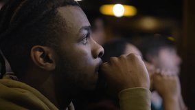 Portrait of African American fan cheering and celebrating when soccer team scores goal and wins the championship. Group of multicultural people watch live football match sitting in sports bar or pub. - Powered by Shutterstock - Get 15% off with code: PIKWIZARD15