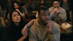 Group of diverse friends together watch live football match broadcast in sports pub on TV. Fans gathered to cheer and support team playing in tournament. Player scores a goal and crowd celebrate. - Powered by Shutterstock - Get 15% off with code: PIKWIZARD15