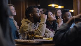 Happy sport fans celebrating and cheering when football team scores goal and wins world league championship. Group of multicultural people applaud and shout watching soccer match live in bar or pub. - Powered by Shutterstock - Get 15% off with code: PIKWIZARD15