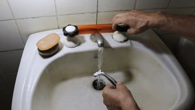 Man washes his razor after shaving in old white bathroom, under running water to clean shaving foam for daily routine personal care 