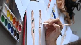 Faceless woman draws sketches of swimwear. Close-up of fashion designer's hands. Vertical video. 