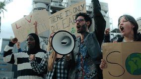 Group of diverse people shouting angrily outdoor manifesting for global warming. Pro-earth demonstration with banners for climate change. Man with megaphone in a protest against pollution in community - Powered by Shutterstock - Get 15% off with code: PIKWIZARD15